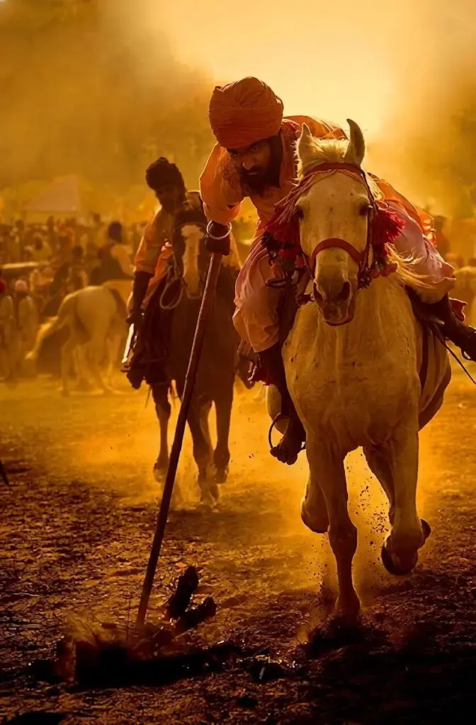 A rider in orange charges through golden dust at full gallop